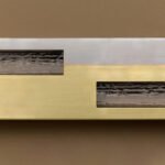 Articolo SEAM sconce, a linear luminaire made of steel and brass, showcasing visible welds as a design feature.