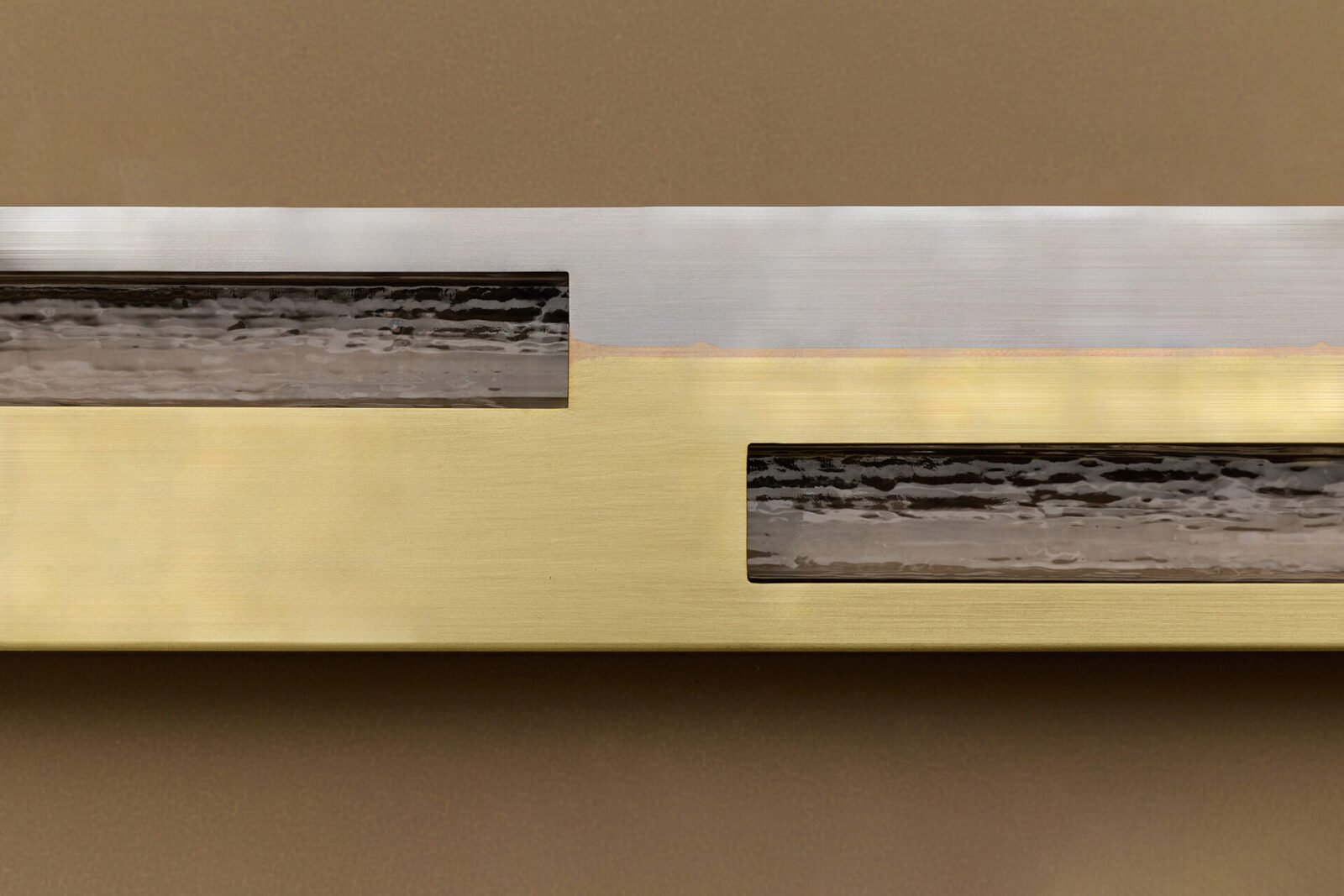 Articolo SEAM sconce, a linear luminaire made of steel and brass, showcasing visible welds as a design feature.
