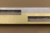 Articolo SEAM sconce, a linear luminaire made of steel and brass, showcasing visible welds as a design feature.
