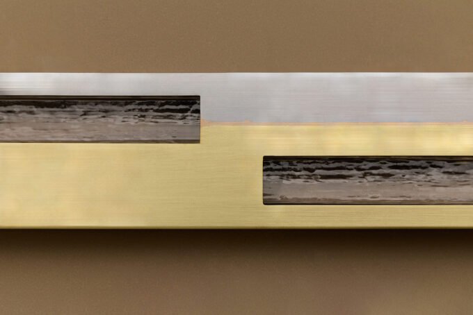 Articolo SEAM sconce, a linear luminaire made of steel and brass, showcasing visible welds as a design feature.