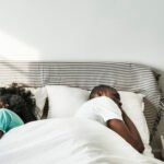 A person lying awake in bed at night, looking stressed, contemplating relationship issues, symbolizing the link between anxious attachment and sleep disturbance.