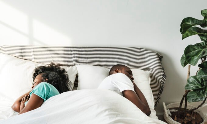 A person lying awake in bed at night, looking stressed, contemplating relationship issues, symbolizing the link between anxious attachment and sleep disturbance.