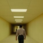 Kane Parsons, director of The Backrooms movie, standing in a dimly lit, mono-yellow hallway reminiscent of the Backrooms aesthetic.