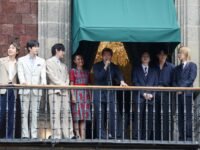 صورة لفرقة BTS على شرفة القصر الوطني في مكسيكو سيتي، مع حشد ضخم من المعجبين في ساحة زوكالو.