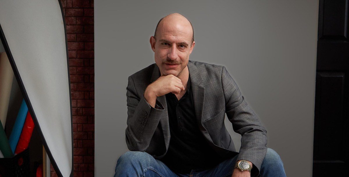 Cecil Baldwin, host of Welcome to Night Vale, in a professional portrait, perhaps with his signature 'dope boots'.