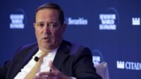 Cisco CEO Chuck Robbins speaks at a summit, symbolizing the company's strategic direction amidst AI-driven growth and workforce restructuring.