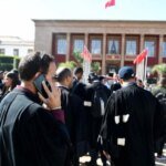 Un groupe d'avocats en robe noire manifestant devant un tribunal au Maroc, symbolisant la crise entre la profession et le ministère de la Justice.