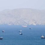 صورة لمضيق هرمز مع سفن عسكرية أو ناقلات نفط، ترمز للتوترات الجيوسياسية في المنطقة.