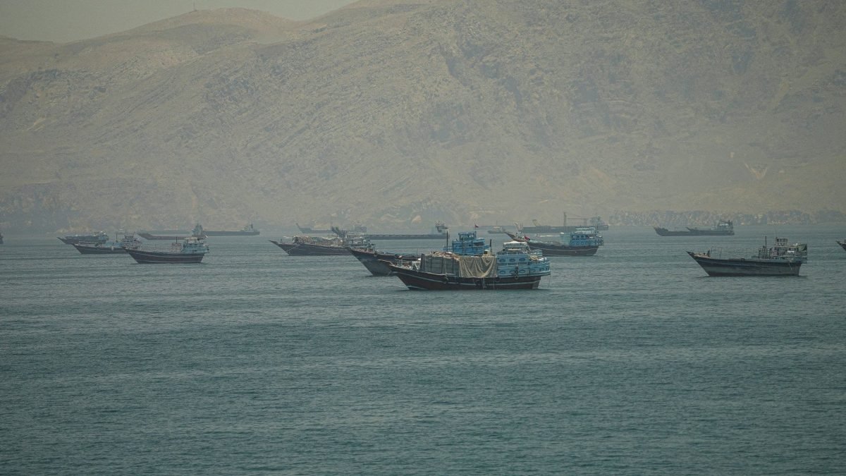 سفن تجارية وناقلات نفط راسية في مضيق هرمز الاستراتيجي، تُظهر التوتر الجيوسياسي المحيط بالمنطقة.