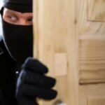 صورة من كاميرات المراقبة تظهر لصاً يحاول فتح باب أمني في سكن طلابي.