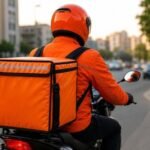 صورة توضيحية لكابتن توصيل من طلبات يحمل طلبًا، مع شعار الشركة في الخلفية، تعكس التغيير في نظام الإكراميات الجديد.