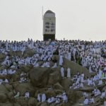 صورة جوية تظهر جموع الحجاج بلباس الإحرام الأبيض يتدفقون من صعيد عرفات إلى مشعر مزدلفة في الليل، مع إضاءة المسارات.