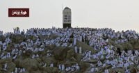 صورة جوية تظهر جموع الحجاج بلباس الإحرام الأبيض يتدفقون من صعيد عرفات إلى مشعر مزدلفة في الليل، مع إضاءة المسارات.