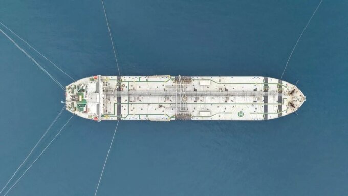 Un pétrolier naviguant dans le détroit d'Ormuz, avec des navires de guerre en arrière-plan, symbolisant les tensions géopolitiques et l'impact sur l'économie.