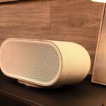 La Denon Home 600, une enceinte connectée de couleur grise, posée sur une surface, mettant en avant son design sobre et sa large grille frontale.