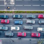 Vue aérienne d'une ville marocaine animée au lever du soleil, avec des voitures sur une autoroute et des immeubles, symbolisant le début d'une journée urbaine épuisante.