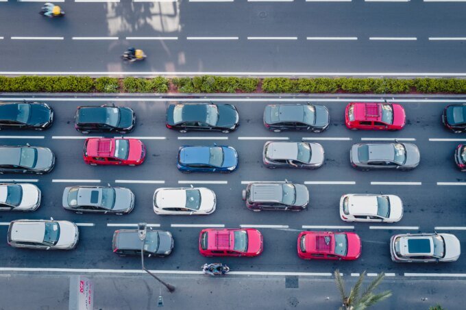 Vue aérienne d'une ville marocaine animée au lever du soleil, avec des voitures sur une autoroute et des immeubles, symbolisant le début d'une journée urbaine épuisante.