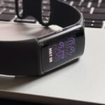 A close-up of a Fitbit device screen displaying health data, with the Fitbit app interface visible on a smartphone in the background, symbolizing the upcoming changes.