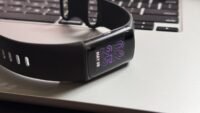 A close-up of a Fitbit device screen displaying health data, with the Fitbit app interface visible on a smartphone in the background, symbolizing the upcoming changes.