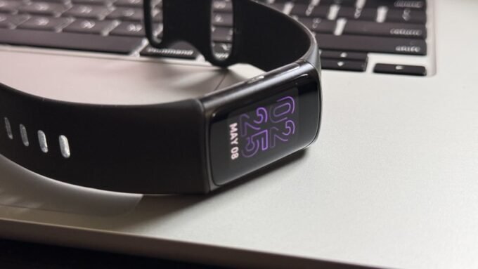 A close-up of a Fitbit device screen displaying health data, with the Fitbit app interface visible on a smartphone in the background, symbolizing the upcoming changes.