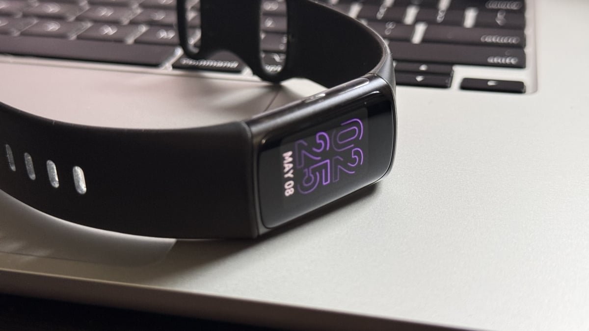 A close-up of a Fitbit device screen displaying health data, with the Fitbit app interface visible on a smartphone in the background, symbolizing the upcoming changes.