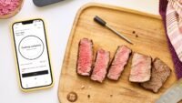 A KitchenAid Smart Thermometer with its probes, displaying temperature readings on a smartphone app.