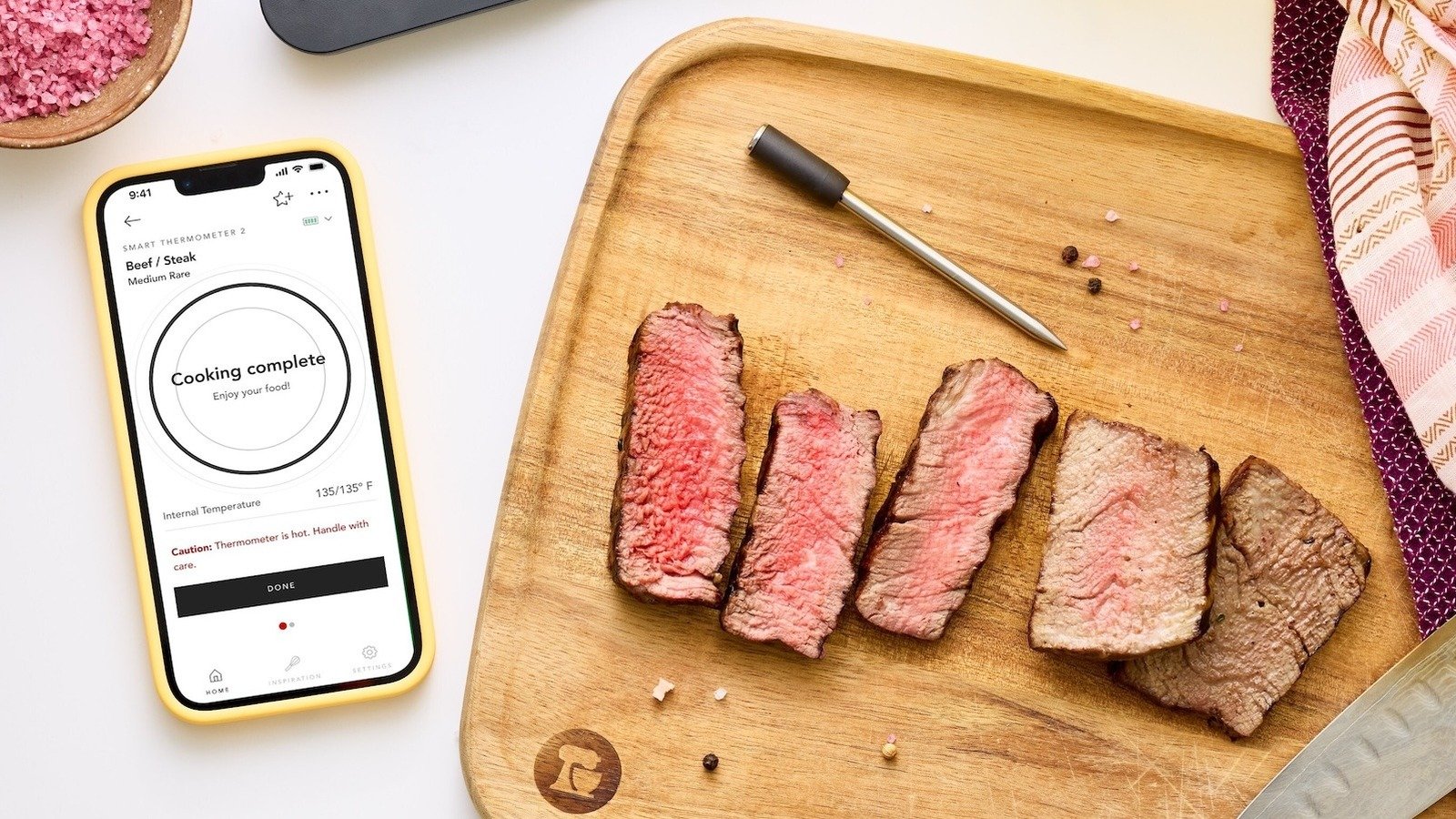 A KitchenAid Smart Thermometer with its probes, displaying temperature readings on a smartphone app.
