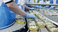 Un rayon de supermarché au Maroc, montrant des étagères partiellement vides de conserves de sardines, symbolisant la pénurie et l'engouement actuel pour ce produit.