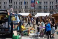 Aerial view of Maker Faire Trieste 2026 in Piazza dell’Unità d’Italia, with tents, exhibits, and the Adriatic Sea in the background.