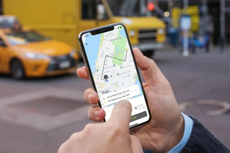 Illustration d'un smartphone affichant une application de transport avec un taxi en arrière-plan, symbolisant la régulation et la modernisation du secteur au Maroc.