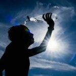 Une personne se protégeant du soleil intense au Maroc, illustrant les défis de la canicule et l'importance des précautions.
