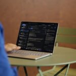 Un homme d'affaires utilisant le nouveau Microsoft Surface Laptop 8 dans un environnement de bureau moderne, avec le Surface Pro 12 visible en arrière-plan.