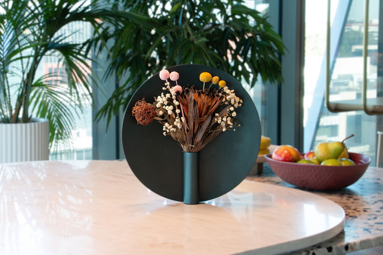 The Nimbus Vase by Ben Peng, a sculptural vessel with a metallic halo-like ring framing flowers, set in a minimalist interior.