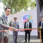 SAR le Prince Héritier Moulay El Hassan, vêtu d'un costume élégant, coupe le ruban inaugural du 31e SIEL à Rabat, entouré de dignitaires français et marocains, symbolisant l'ouverture du salon du livre.
