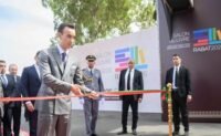 SAR le Prince Héritier Moulay El Hassan, vêtu d'un costume élégant, coupe le ruban inaugural du 31e SIEL à Rabat, entouré de dignitaires français et marocains, symbolisant l'ouverture du salon du livre.