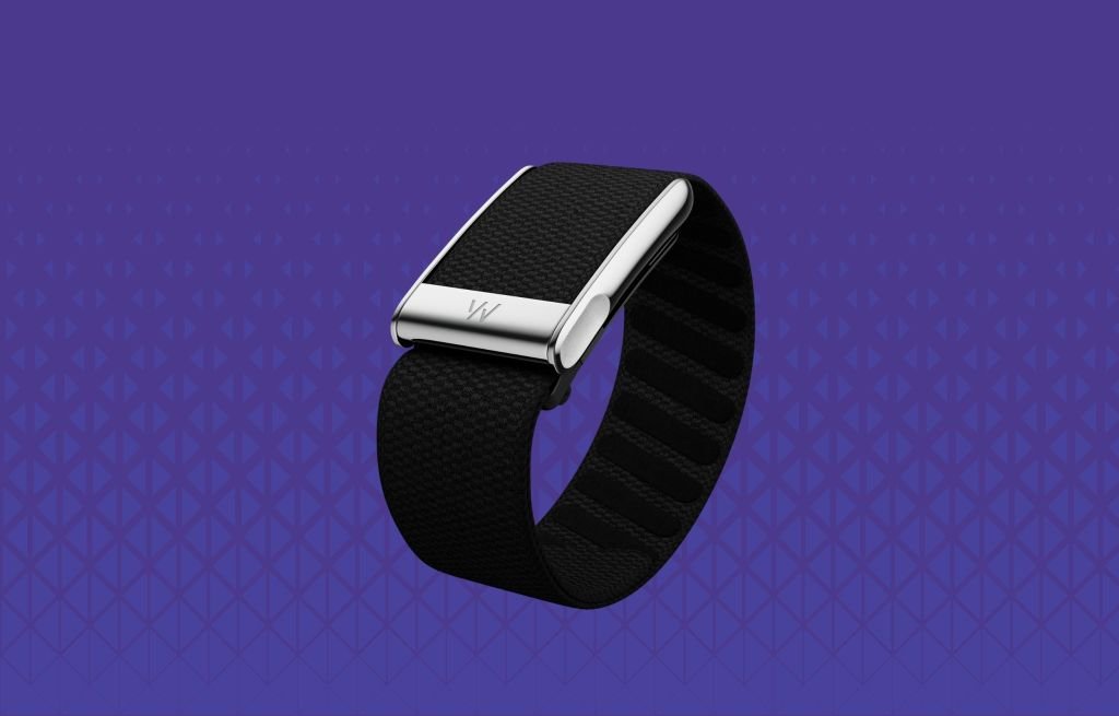 A collection of modern screenless fitness trackers, including a Whoop band, Oura ring, and Fitbit Air device, symbolizing the trend towards discreet wearable technology.