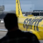 A bright yellow Spirit Airlines plane at an airport gate, symbolizing the airline's unique brand and its current financial struggles.