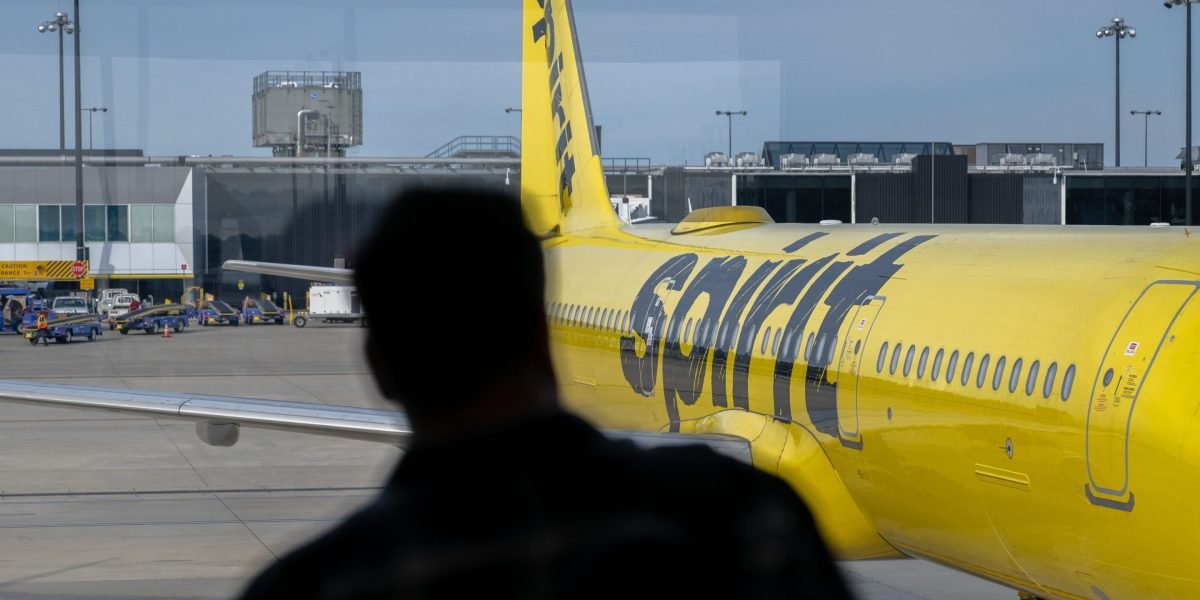 A bright yellow Spirit Airlines plane at an airport gate, symbolizing the airline's unique brand and its current financial struggles.