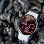 A Pixel Watch 4 displaying Wear OS 7 features, including new Wear Widgets and live updates.