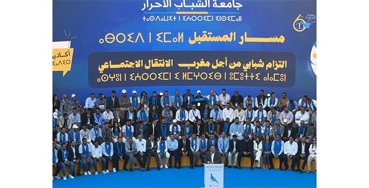 Mohamed Chaouki, président du RNI, s'exprimant devant une assemblée de jeunes lors de l'Université d'été de la jeunesse RNI à Agadir, avec un public attentif en arrière-plan.
