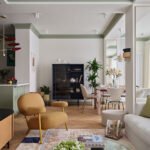 Stylish living room in an Almaty apartment featuring sage walls, mirrored columns, and curated modern furnishings.