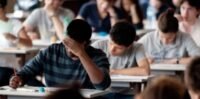Des lycéens révisant ensemble avec des livres et des cahiers, symbolisant l'effort et le soutien scolaire pour le baccalauréat.
