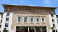 Le siège moderne de Bank Al-Maghrib à Rabat, symbolisant la stabilité monétaire et la gestion économique prudente du Maroc, avec des graphiques financiers en arrière-plan.