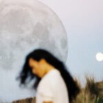 A vibrant full moon glowing in a night sky, with subtle hints of strawberry fields below.