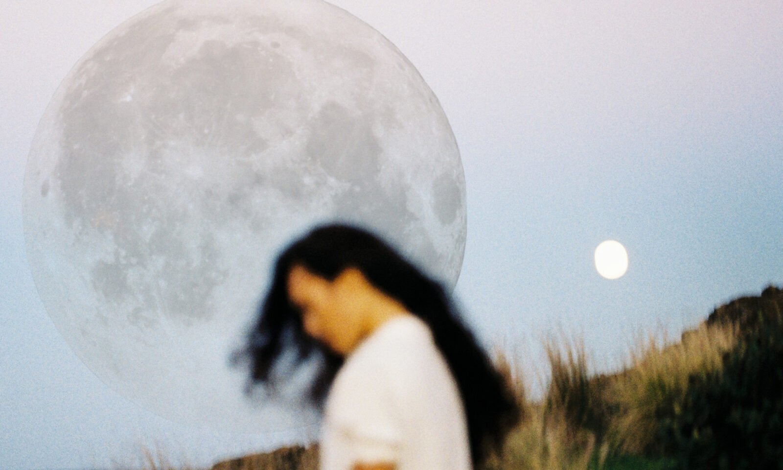 A vibrant full moon glowing in a night sky, with subtle hints of strawberry fields below.
