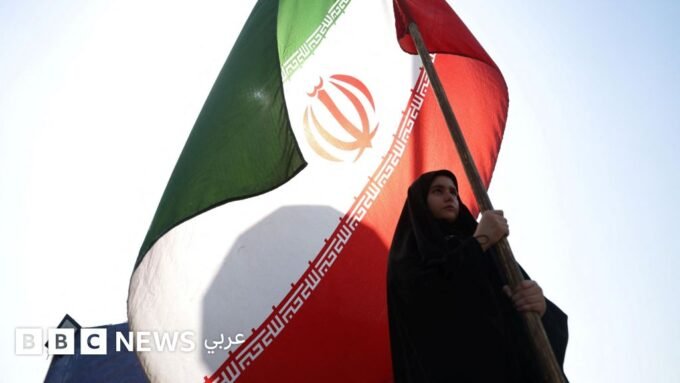 امرأة تحمل العلم الإيراني في أحد شوارع طهران، وسفن تجارية تعبر مضيق هرمز قبالة مسندم في عُمان.