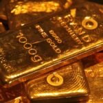صورة لسبائك ذهبية متراكمة مع خلفية لسوق المال، تعكس تراجع أسعار الذهب العالمية.
