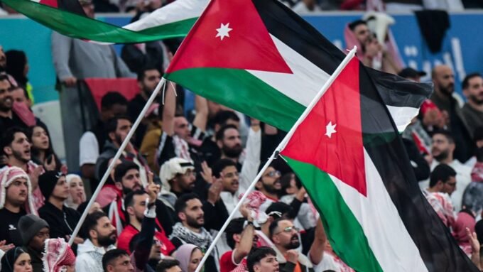 صورة توضيحية لشعار السفارة الأردنية في واشنطن مع خلفية لملعب كرة قدم، تعكس التنبيهات الصادرة للجماهير.