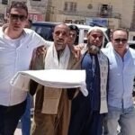 صورة لمسؤولين أمنيين وأفراد من عائلتين يشاركون في جلسة صلح عرفي، مع وجود الكفن كرمز للتسامح في المنيا.