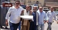صورة لمسؤولين أمنيين وأفراد من عائلتين يشاركون في جلسة صلح عرفي، مع وجود الكفن كرمز للتسامح في المنيا.